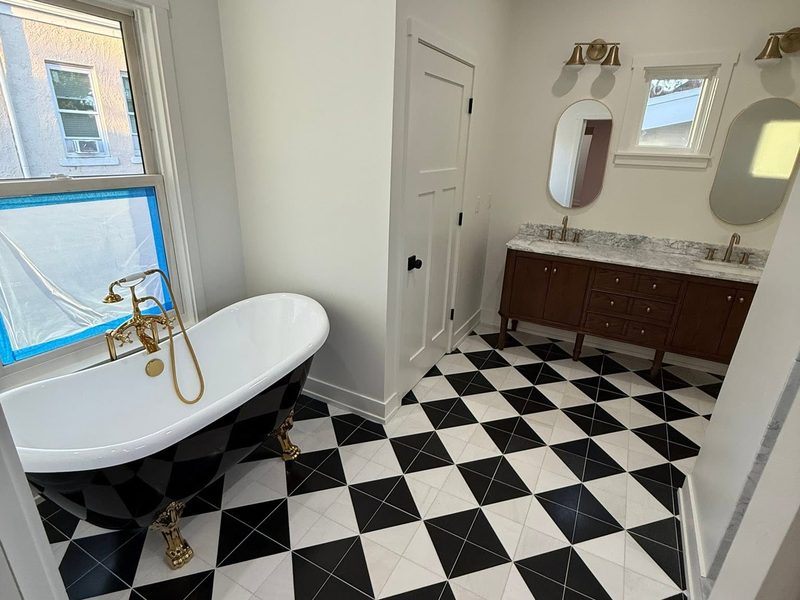Clean bathroom with a clawfoot tub, brass filler and a black and white checkered tile floor