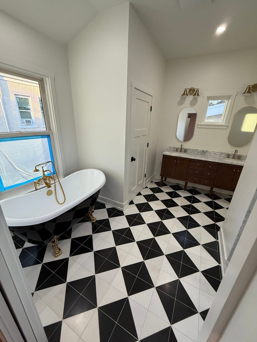 Clean bathroom with a clawfoot tub, brass filler and a black and white checkered tile floor