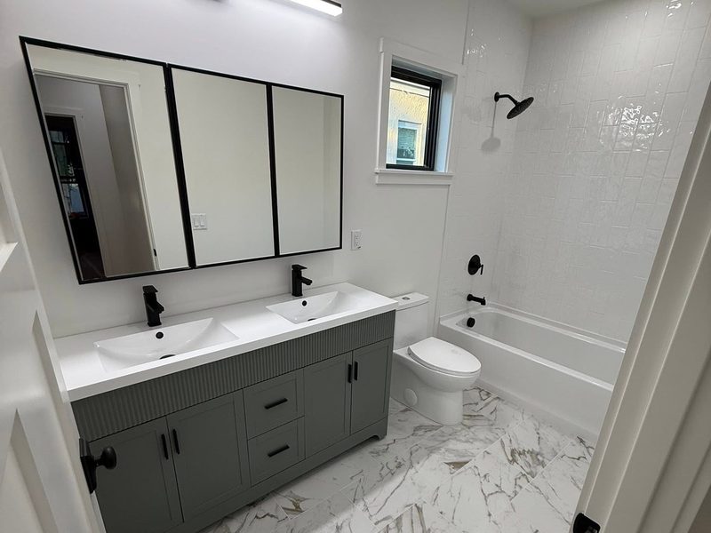 Deep cleaned bathroom with a double vanity, black fixtures and a polished marble tile floor