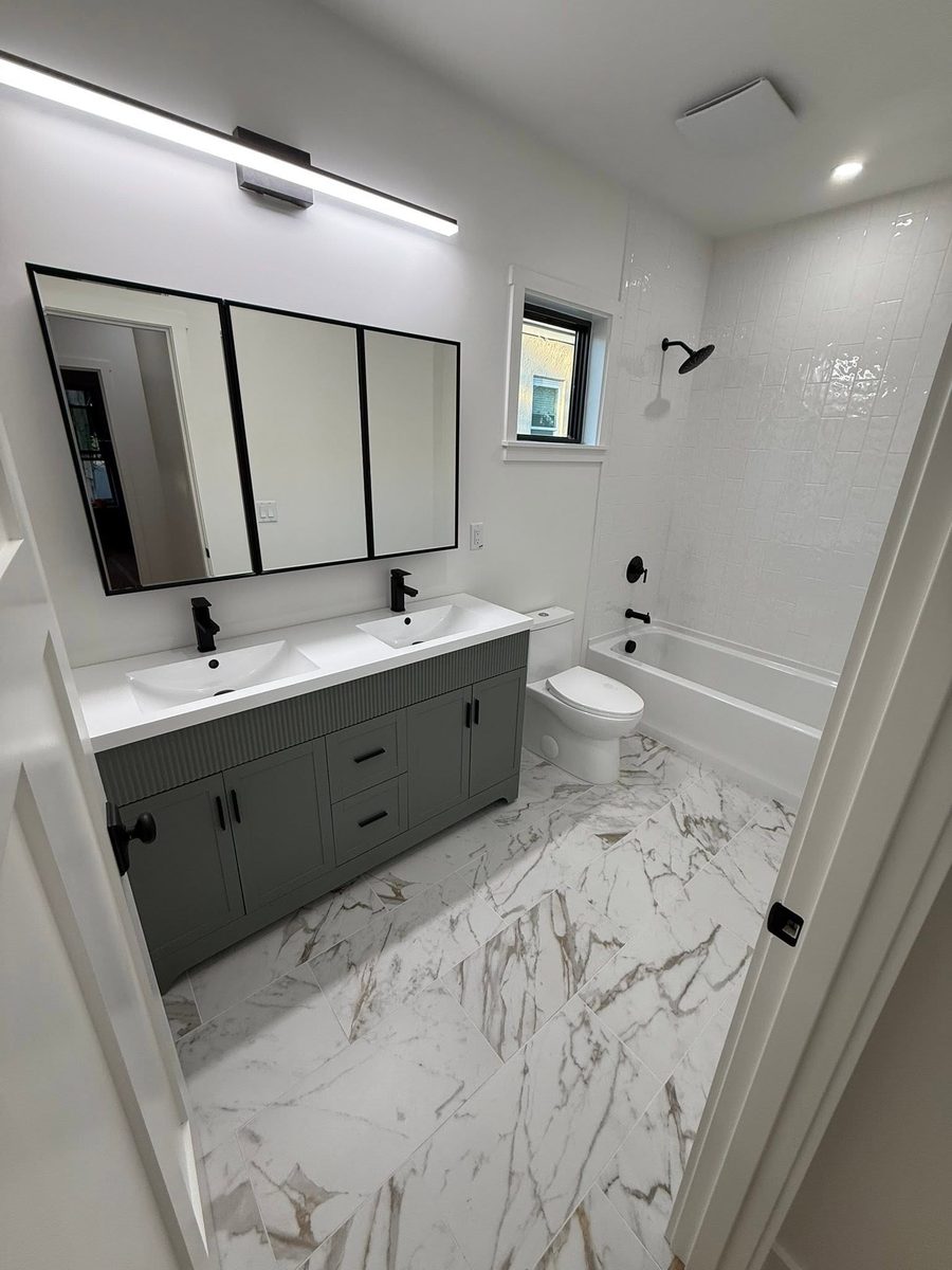 Deep cleaned bathroom with a double vanity, black fixtures and a polished marble tile floor
