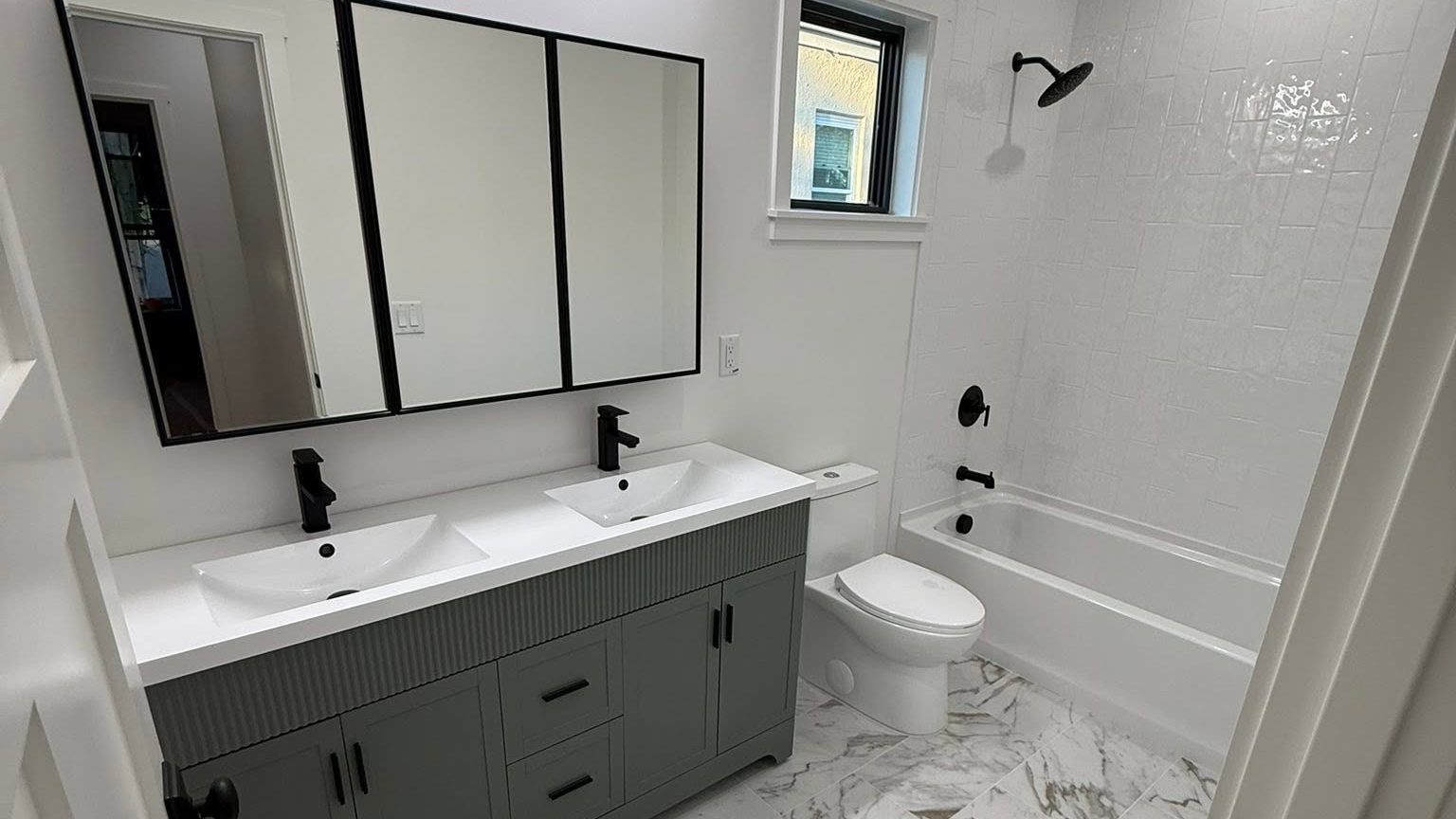 Deep cleaned bathroom with a double vanity, black fixtures and a polished marble tile floor
