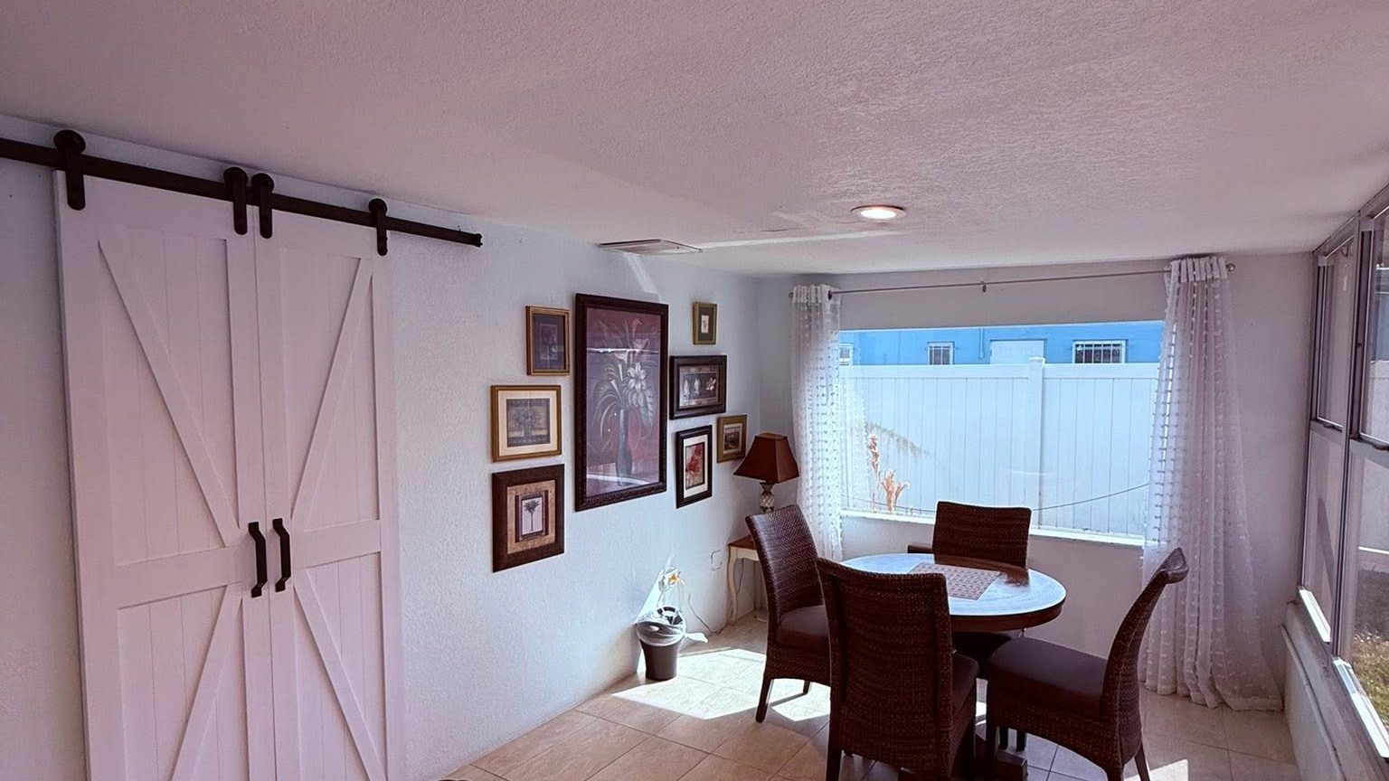 Cleaned dining area with a sliding barn door, tiled floor and dusted decor